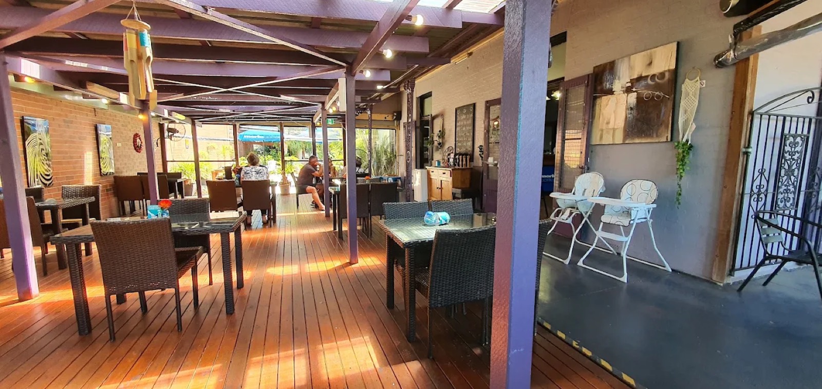 The covered outdoor deck at Zeebras with warm timber floors and a purple pergola